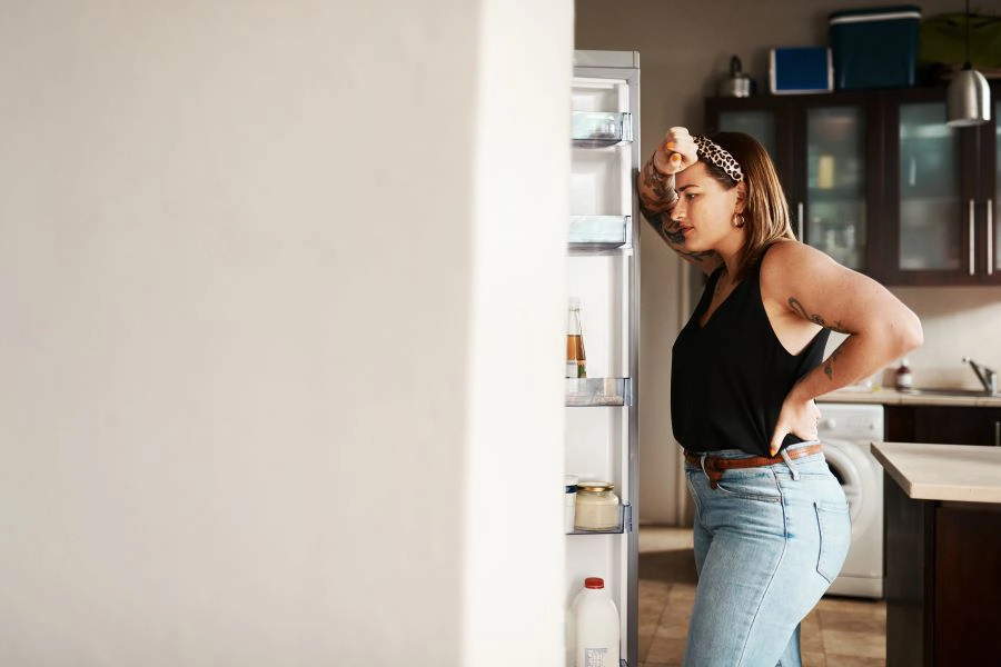 Woman unsure what to take from the fridge.